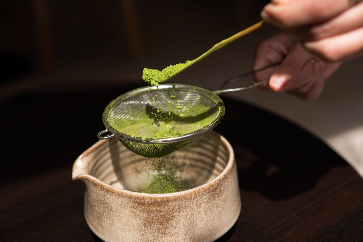 Sifting matcha through a small strainer into the bowl